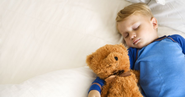 sleeping toddler boy snuggling a teddy bear.