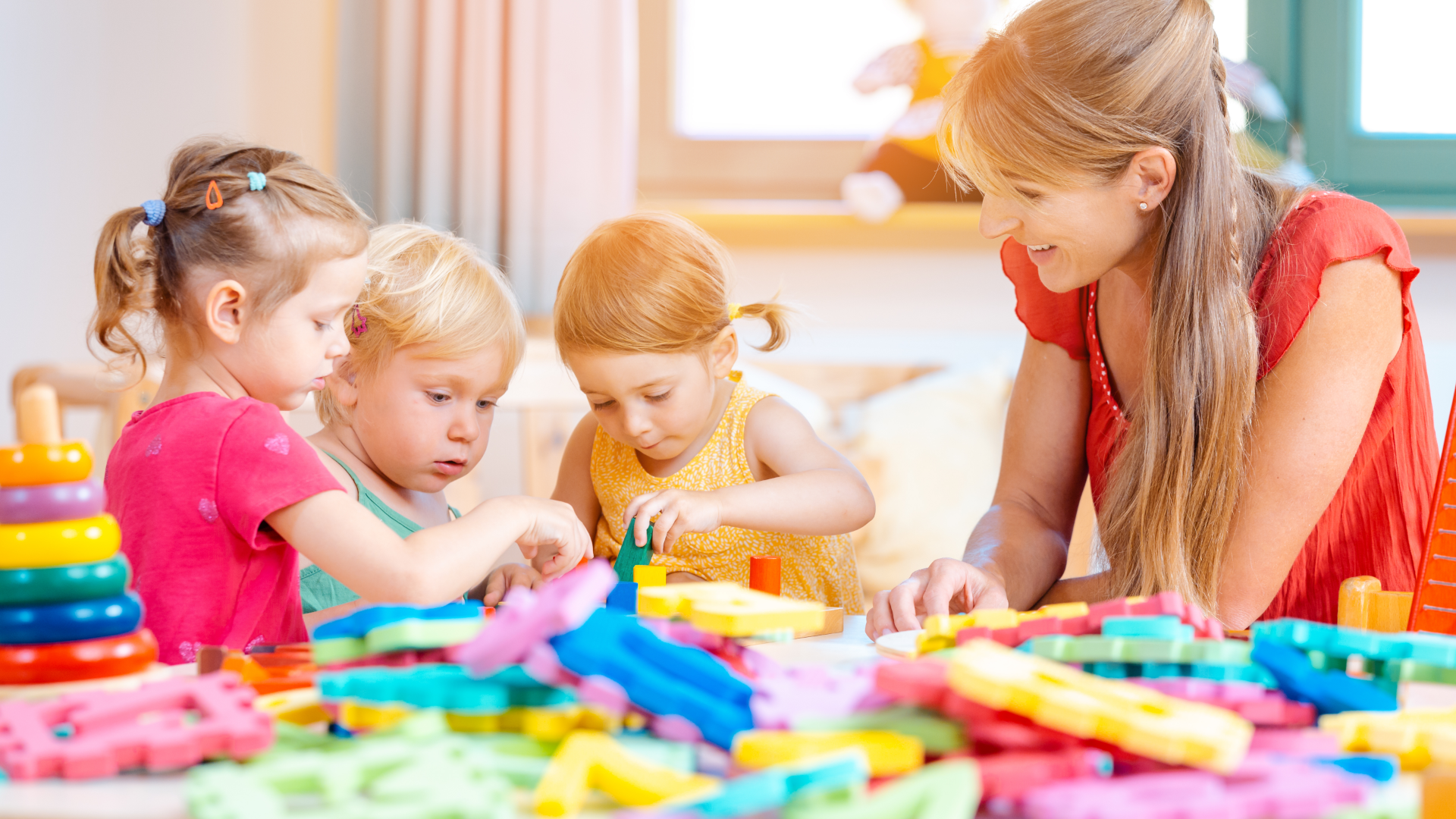 Three children and their nanny playing with colorful blocks