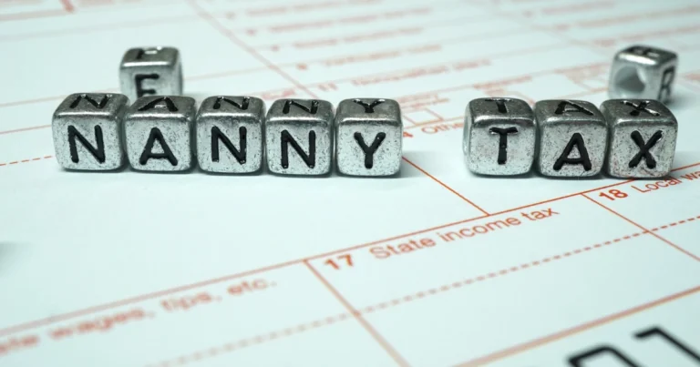 Letter blocks spelling “Nanny Tax” placed on top of an income tax form
