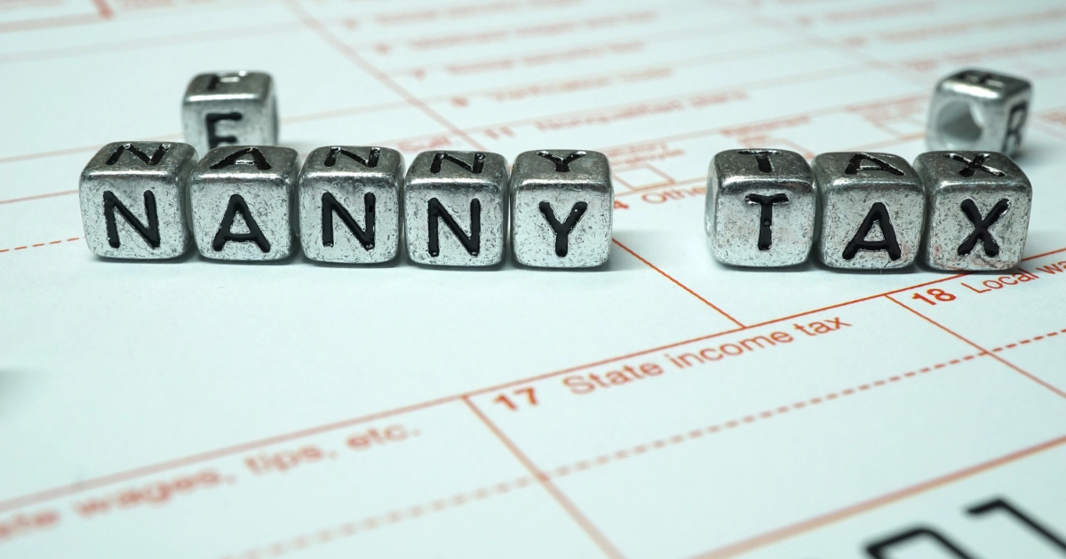Letter blocks spelling “Nanny Tax” placed on top of an income tax form