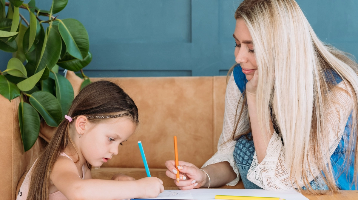 Full-time nanny drawing pictures with a child in the summertime